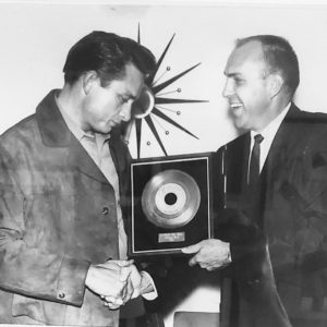 One white man giving a framed record album to another white man
