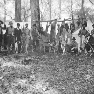 Large group of white men with guns and dogs and dead animals