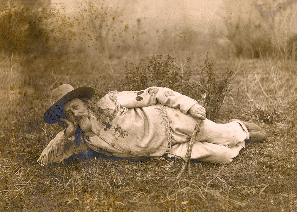 Older white man with long hair and beard lying down on his side on the ground