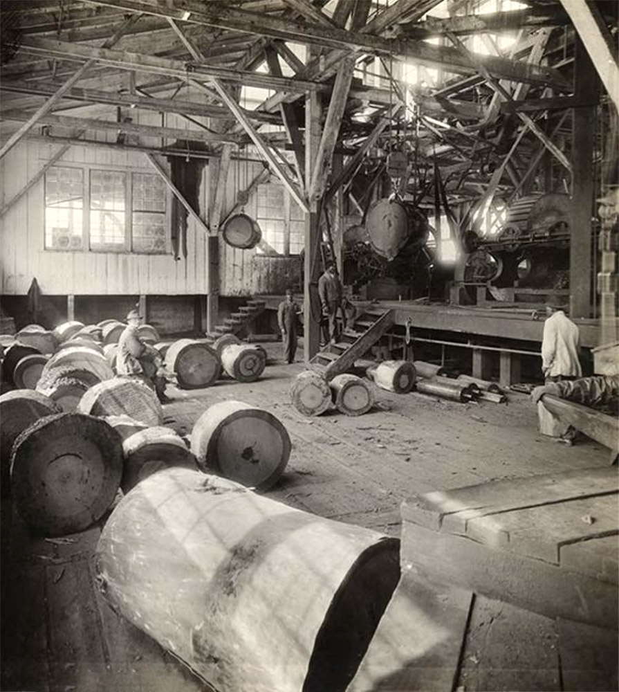 White men working in factory with machines and large cylindrical objects