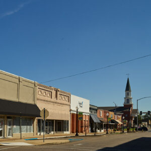 Storefront buildings lining street with church steeple in background