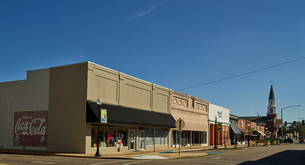 Storefront buildings lining street with church steeple in background