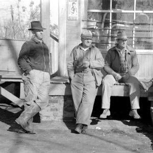 Four white men in hats lounging on porch of store
