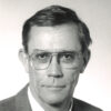 White man in suit and tie and wearing glasses