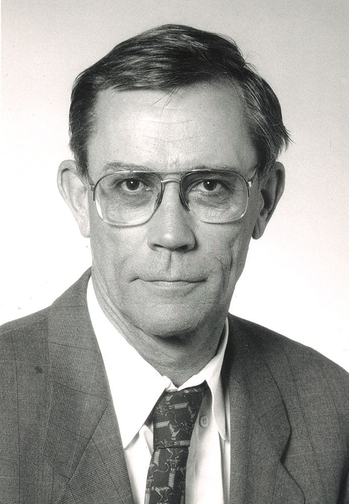 White man in suit and tie and wearing glasses