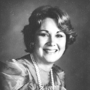 White woman wearing dress and pearl necklace