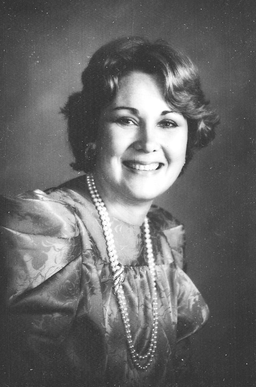 White woman wearing dress and pearl necklace