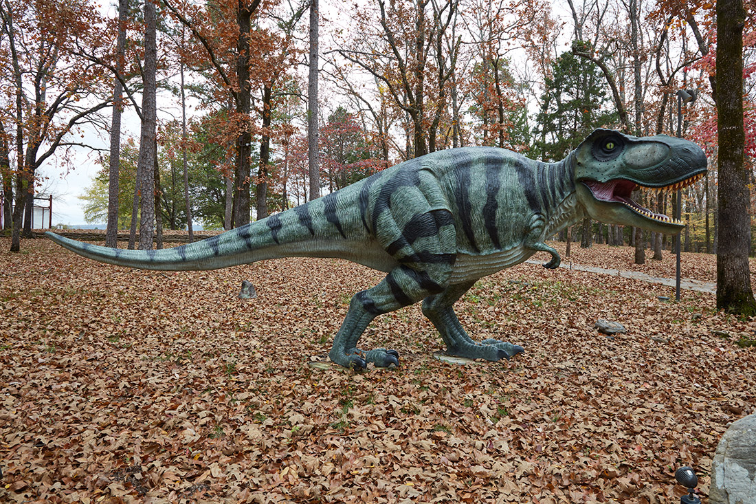 Statue of a dinosaur in wooded area
