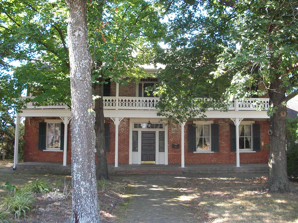 Multistory red brick house with second story porch