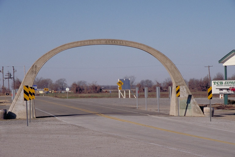 Concrete arch straddling highway and saying "Entering Arkansas"