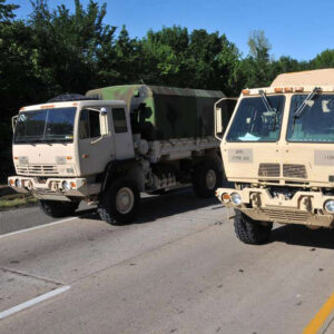 Two military vehicles parked on road near flooded section