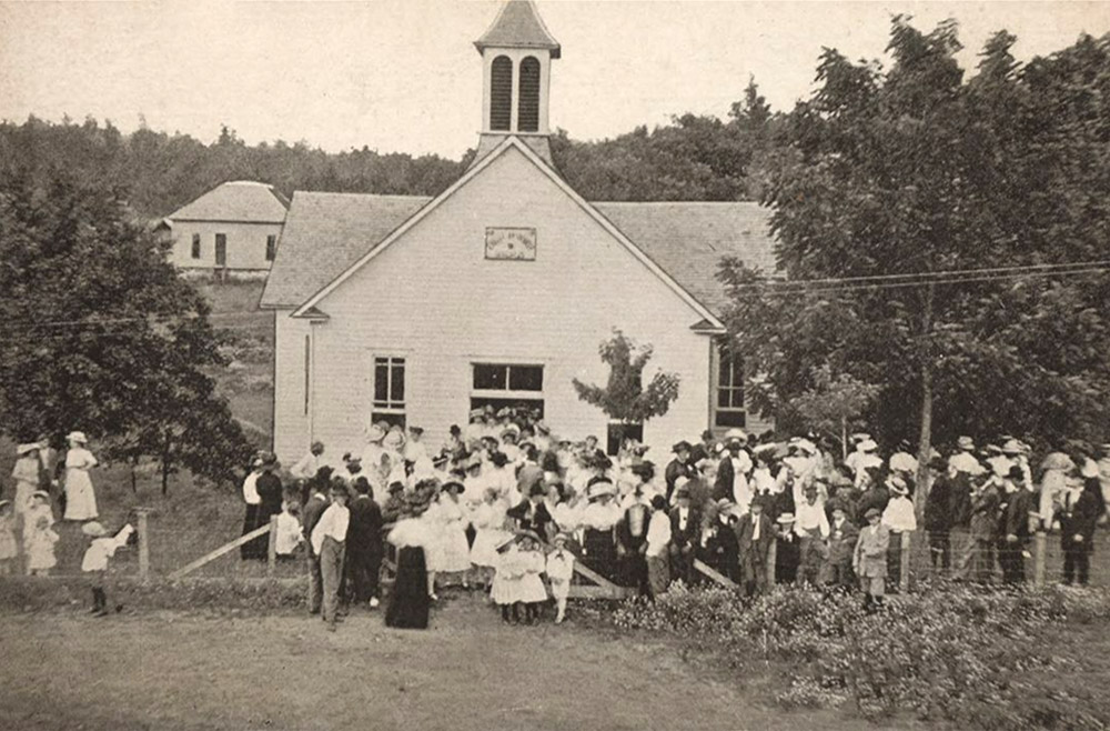 Large crowd of white people in front of multistory wooden church building