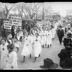 Nurses in uniform marching in parade while spectators view