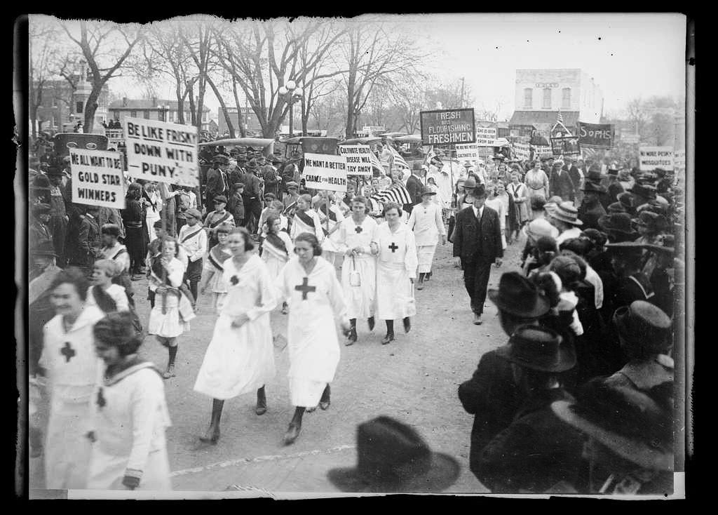 Nurses in uniform marching in parade while spectators view
