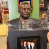 Bronze bust of man on a display with a plaque and photo beneath