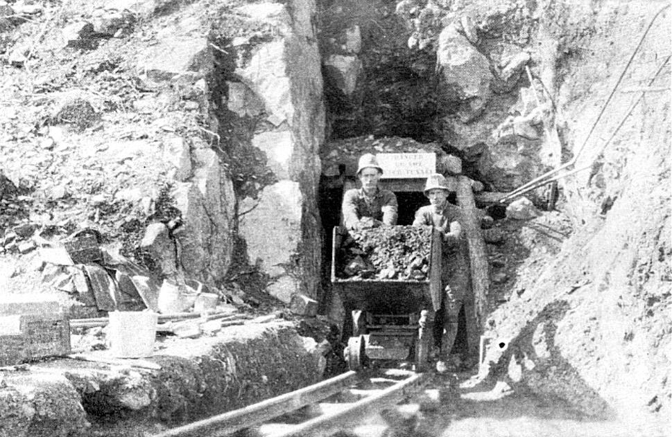 Two white men emerging from a tunnel with a cart