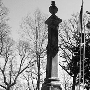 Tall stone grave monument with "Cleburne" engraved on it surrounded by bare trees