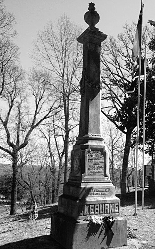 Tall stone grave monument with "Cleburne" engraved on it surrounded by bare trees