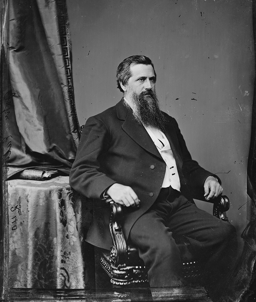 White man with beard sitting in chair