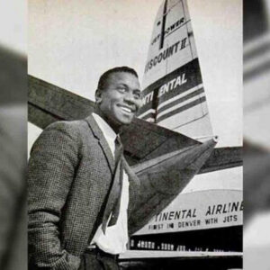 African American man in suit standing in front of airplane