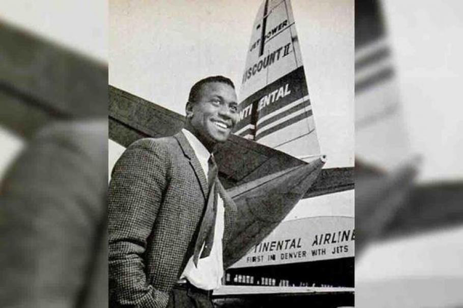 African American man in suit standing in front of airplane