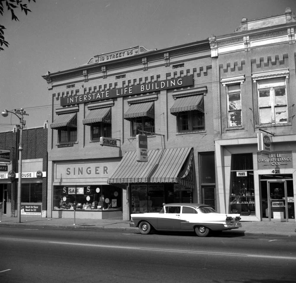 Different storied storefront buildings with car parked at curb in front