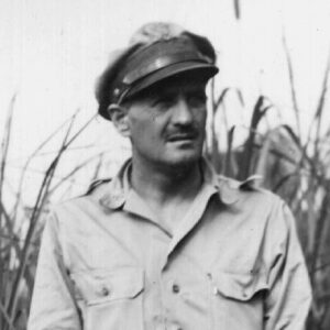 White man in military garb with tall grass in background