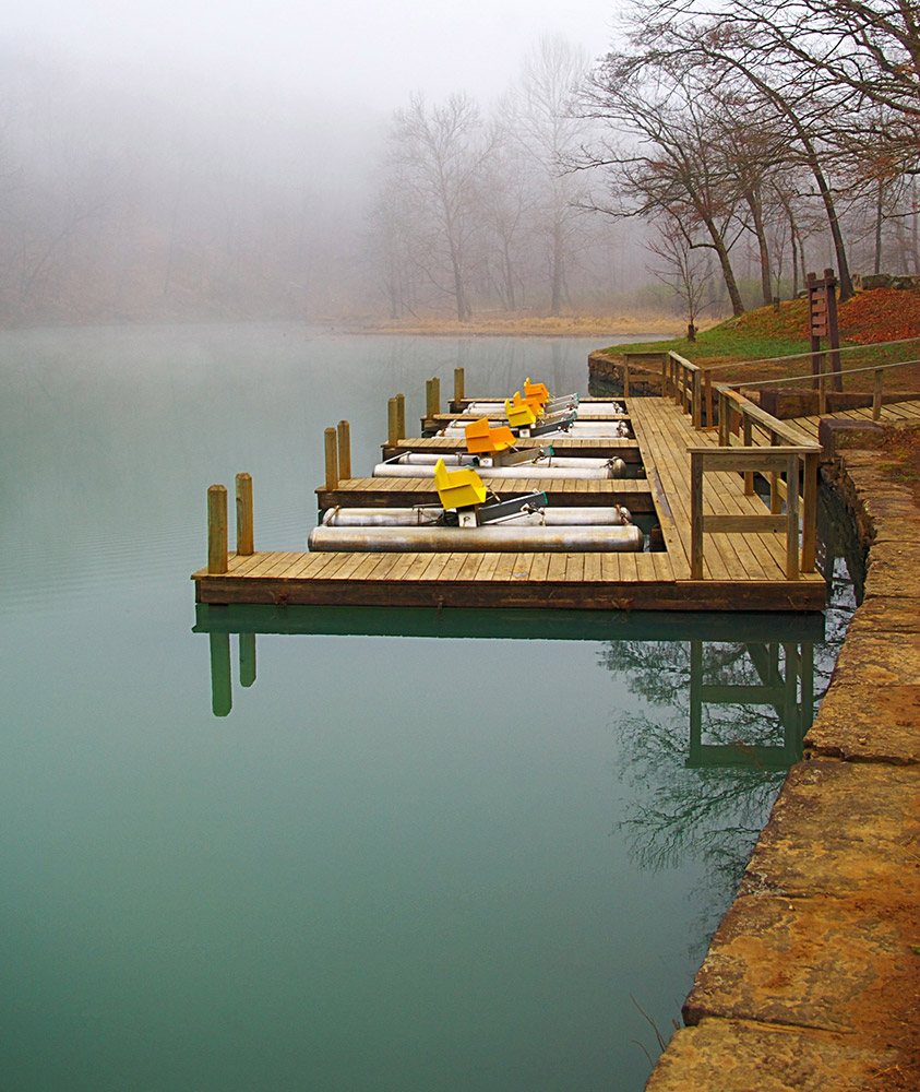 four pedalboats with yellow and orange seats sitting in water at dock