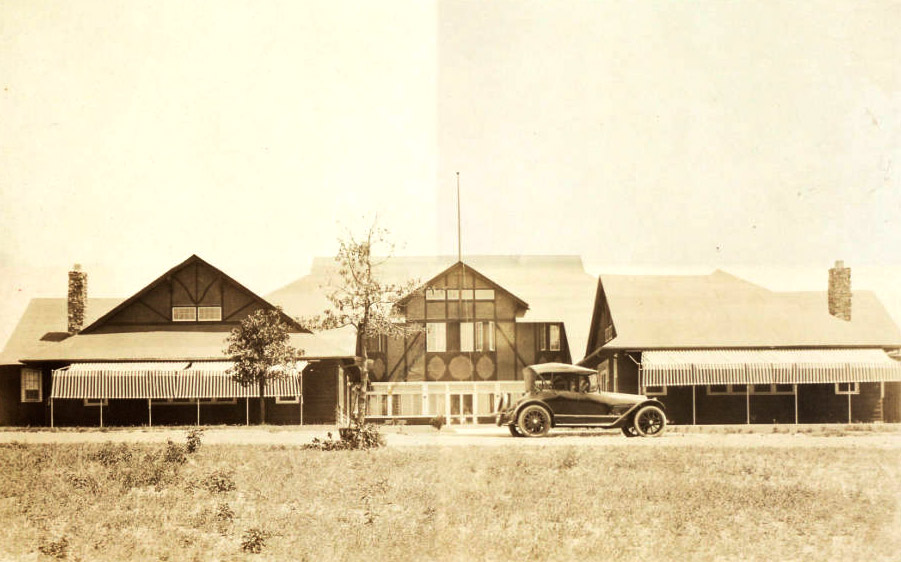 Multistory wooden buildings with an early automobile parked out front