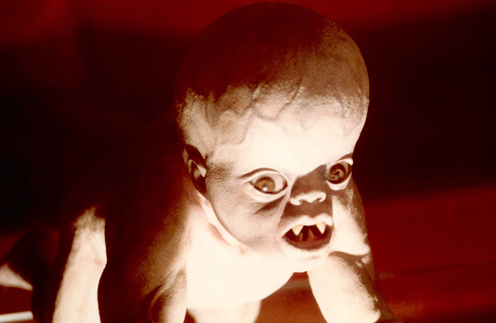 Demonic looking baby with swollen head and pointed teeth