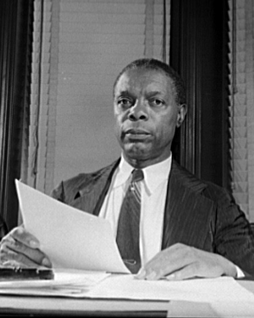 African American man sitting at desk holding sheets of paper
