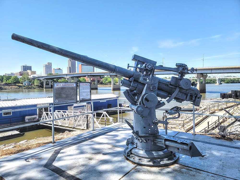 Large mounted gun with river and city in background