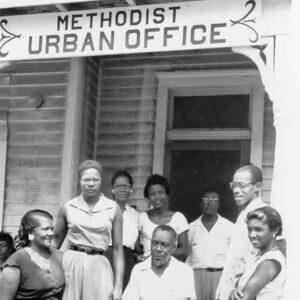 African American men and women and one child in front of building with sign saying "Methodist Urban Office"