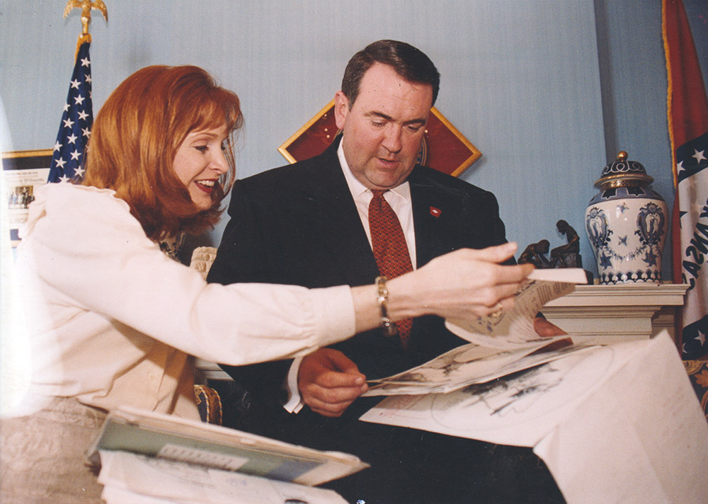White woman and white man in suit seated at table looking at papers