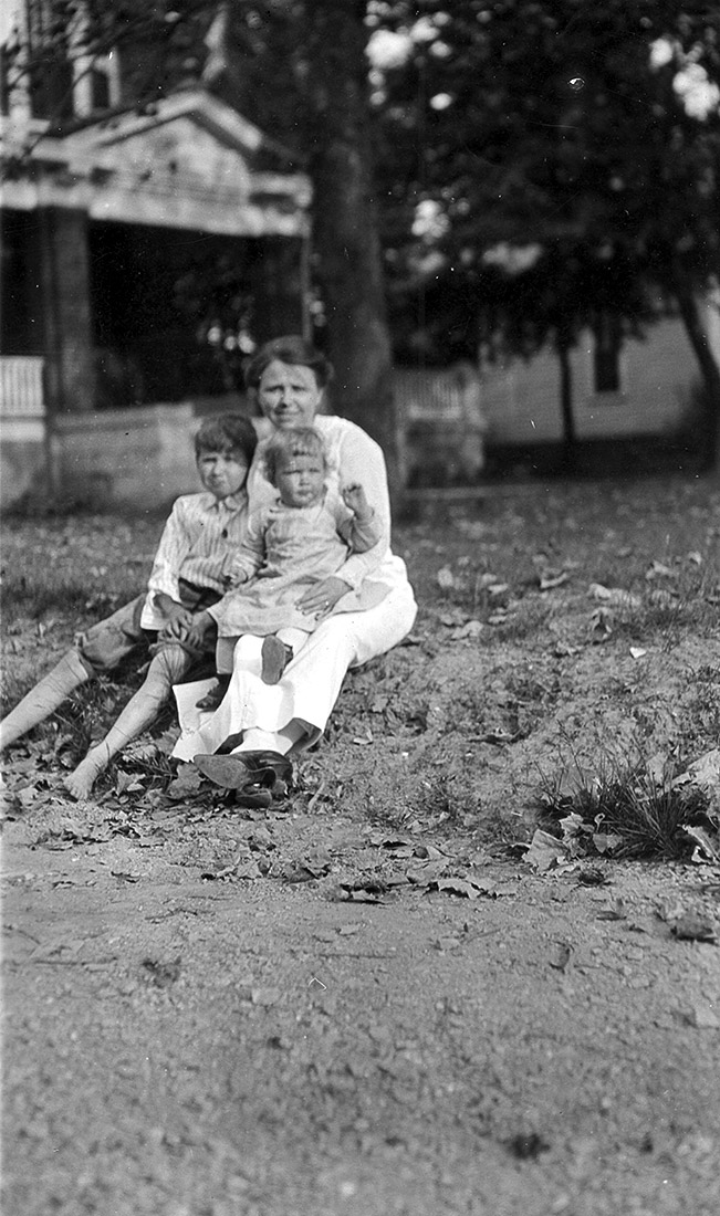 White woman and two white children sitting on grass