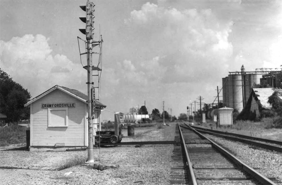 Small white wooden building next to railroad tracks