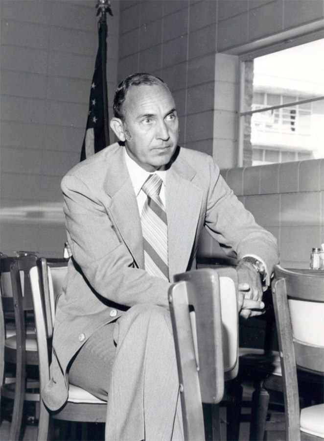 White man in suit and tie seated