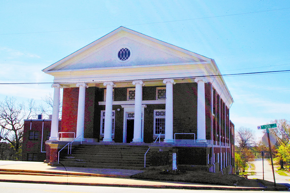 Red brick multistory church building with grand white columns and porch