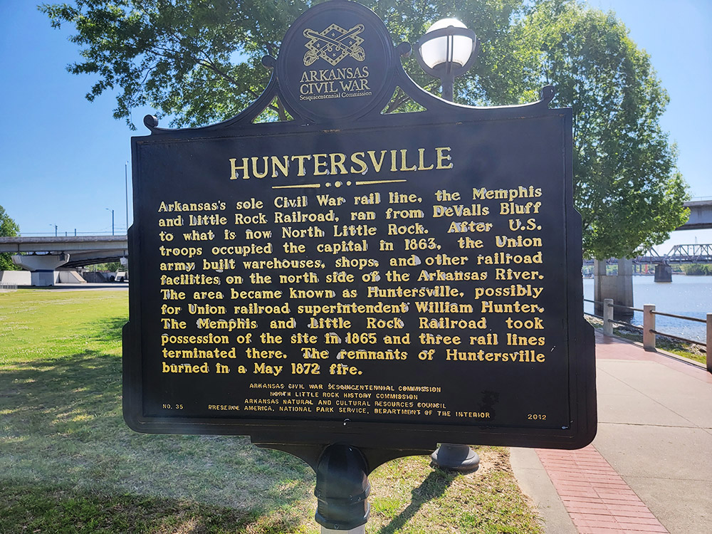 Black sign with yellow letters giving historical information about Huntersville