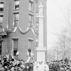 Large number of people gathered around a statue of a soldier