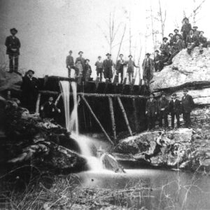 People standing atop and alongside wooden dam