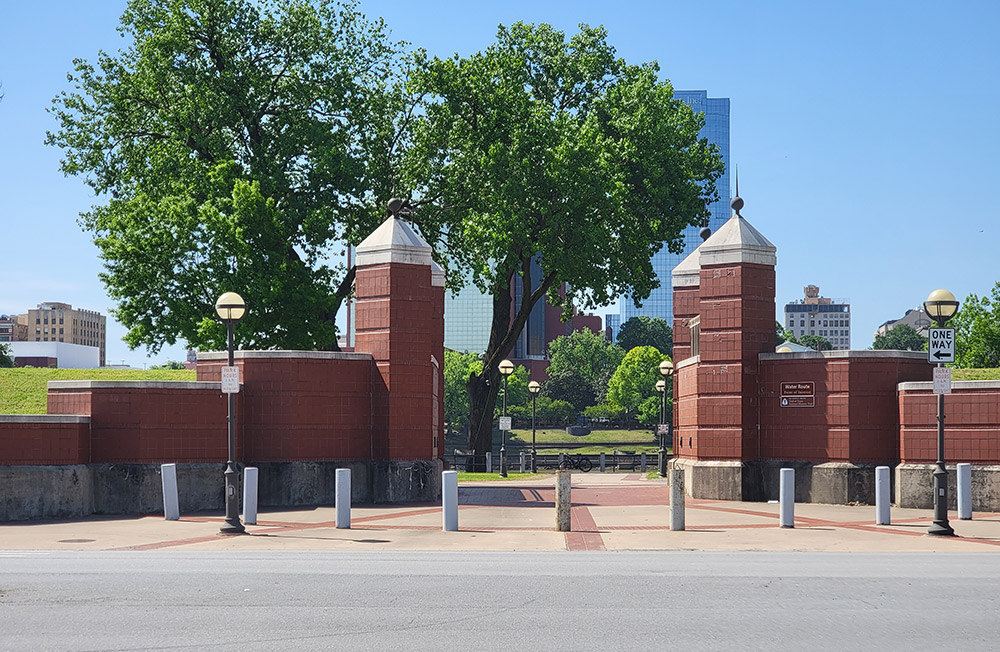 Red brick gate with trees and buildings in the background