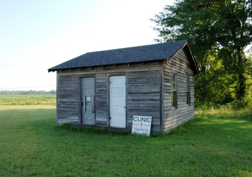 Single story wooden house with sign saying "Clinic Hawkins"