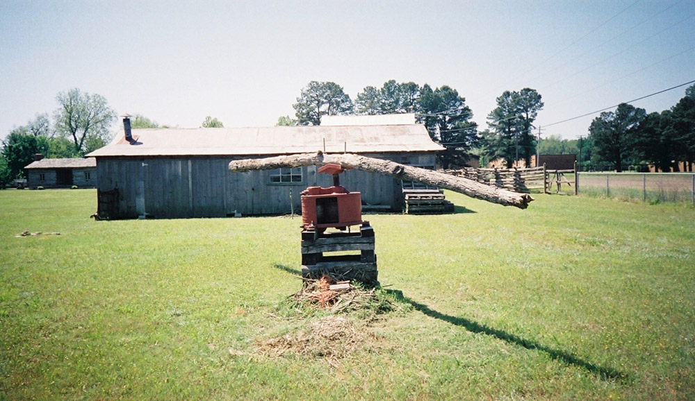 Long log attached to machine with building behind