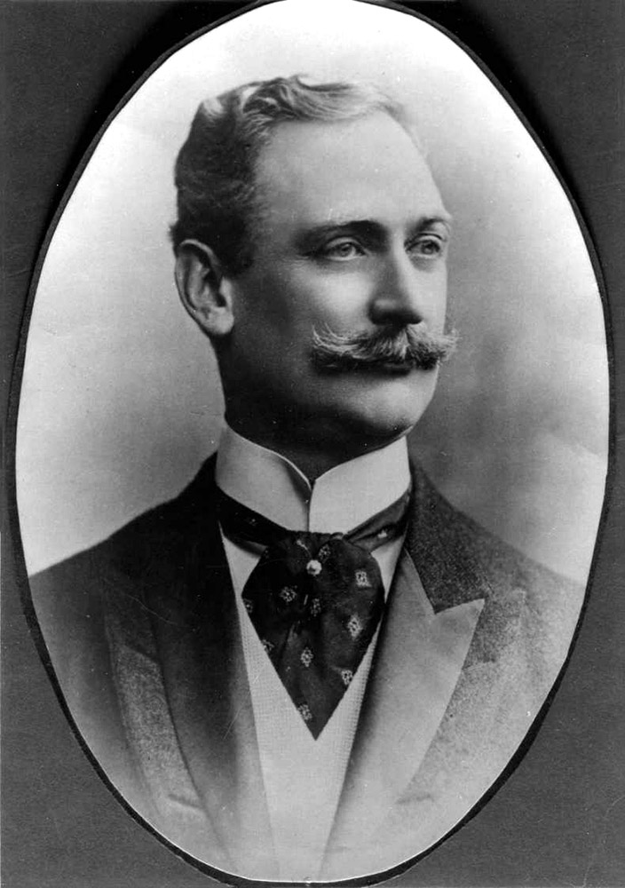 White man in suit with mustache and cravat