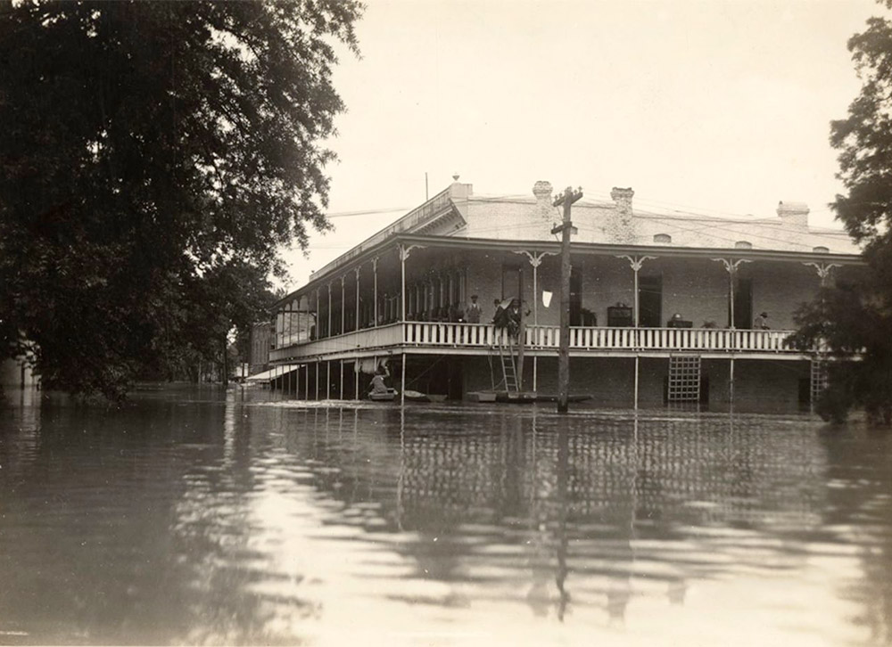 Buildings half underwater with people standing on second story porch