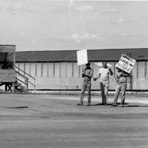 Three men carrying picket signs in front of building