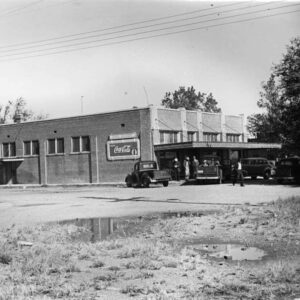 rectangular brick building with people and cars out front