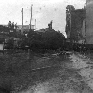 People sitting and standing by a wrecked train