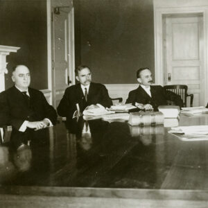 Group of white men in suits sitting at table